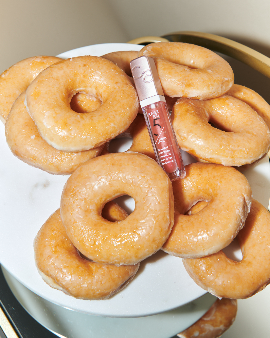 lip gloss on a pile of glazed ring donuts, glazed donut skin, glazed donuts, beauty, beauty trend, the suite, the suite edit, brutal fruit