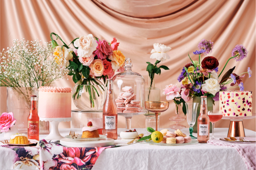 brunch spread with cake, spritzers and brutal fruit, the suite, the suite edit, entertaining, hosting, table decorating ideas, florals, satin, flowers